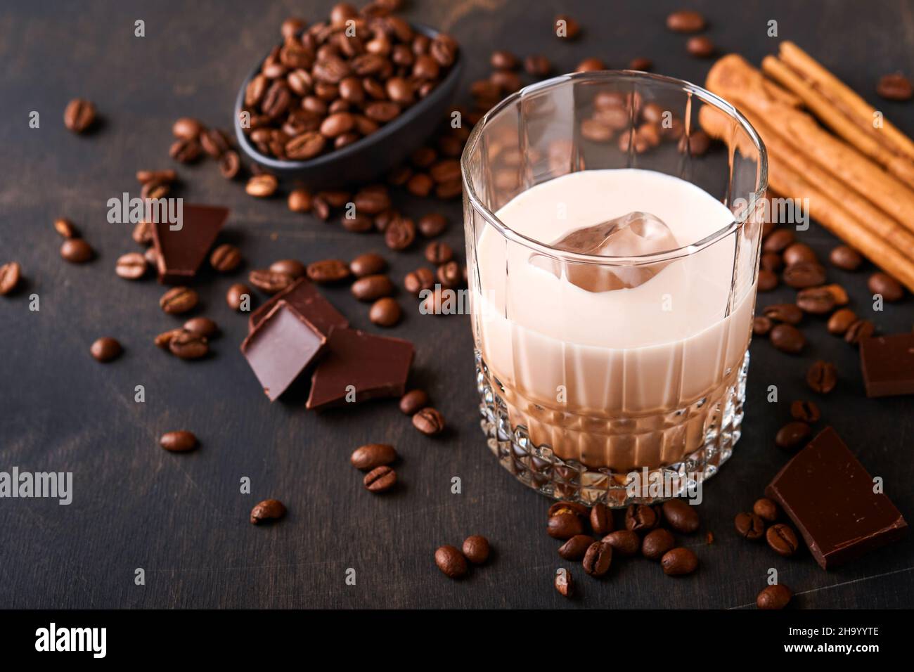 Verre de liqueur baileys à la crème irlandaise avec grains de café rôtis, cannelle et chocolat sur table en bois sombre.Mise au point sélective. Banque D'Images