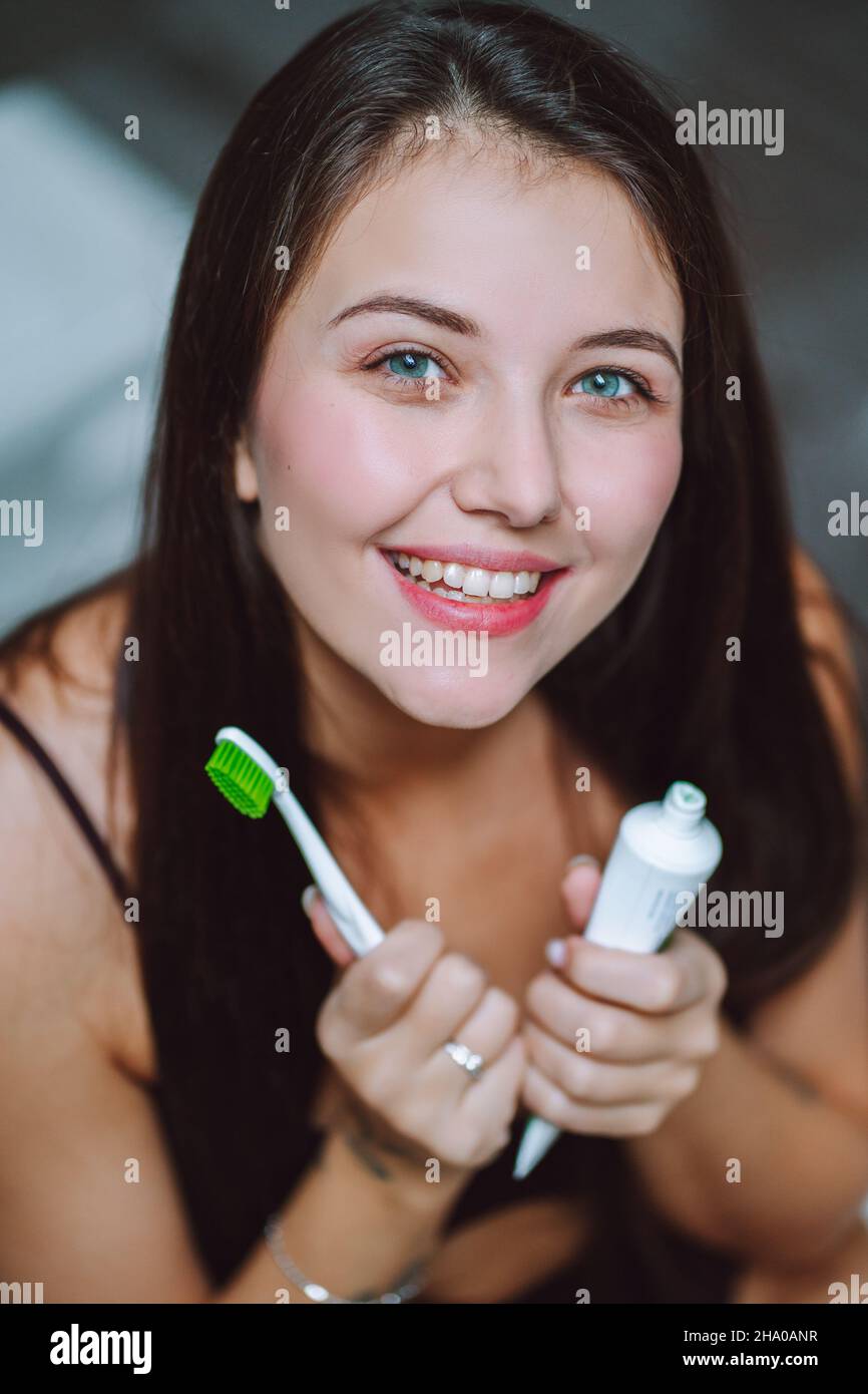 Fermer est le portrait d'une jeune femme tenant du dentifrice et une brosse à dents.Feemale regarde dans l'appareil photo et souriez avec des dents blanches de neige. Banque D'Images