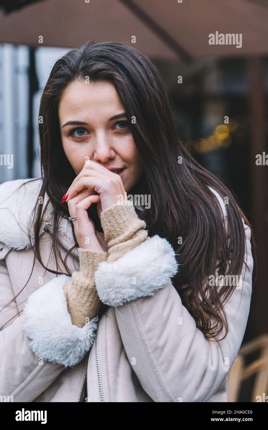 Belle femme souriante avec de longs cheveux portant veste chaude marcher dans la rue chaud hiver européen.Protection des cheveux contre le froid, soins capillaires. Banque D'Images