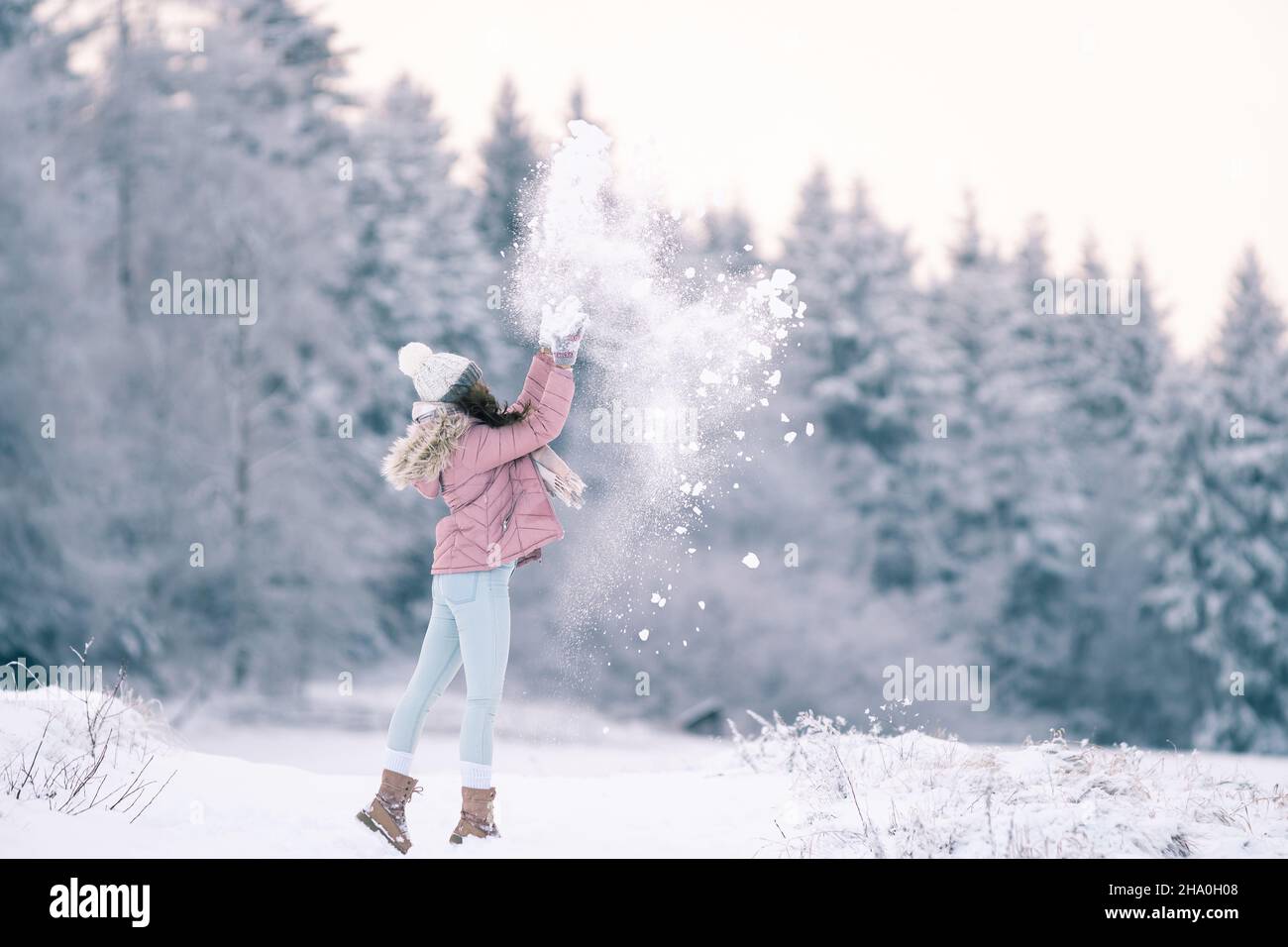 Bienvenue hiver, bonne fille, la femme aime l'hiver et joue avec la neige  au milieu d'un paysage enneigé, dans des vêtements chauds avec un chapeau  et des gants, froid et C Photo