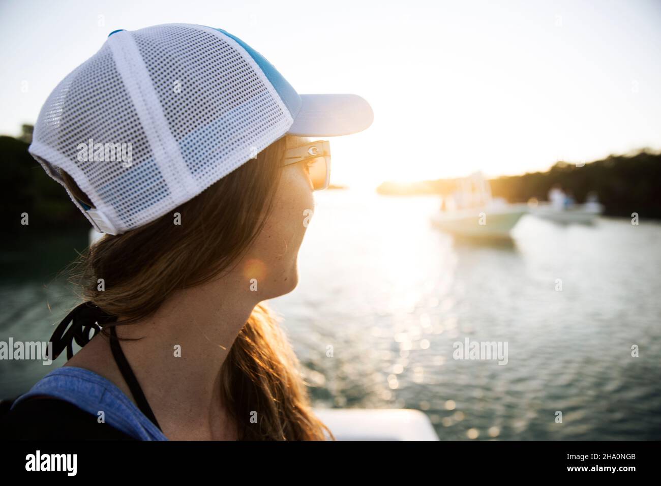 Une femme en chapeau et lunettes de soleil regarde les bateaux au soleil Banque D'Images