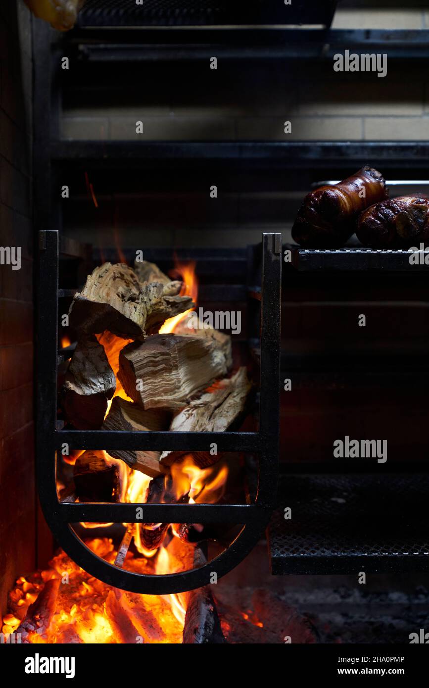 Grill au bois avec bûches de fumée et viande fumée au feu dans un restaurant Banque D'Images