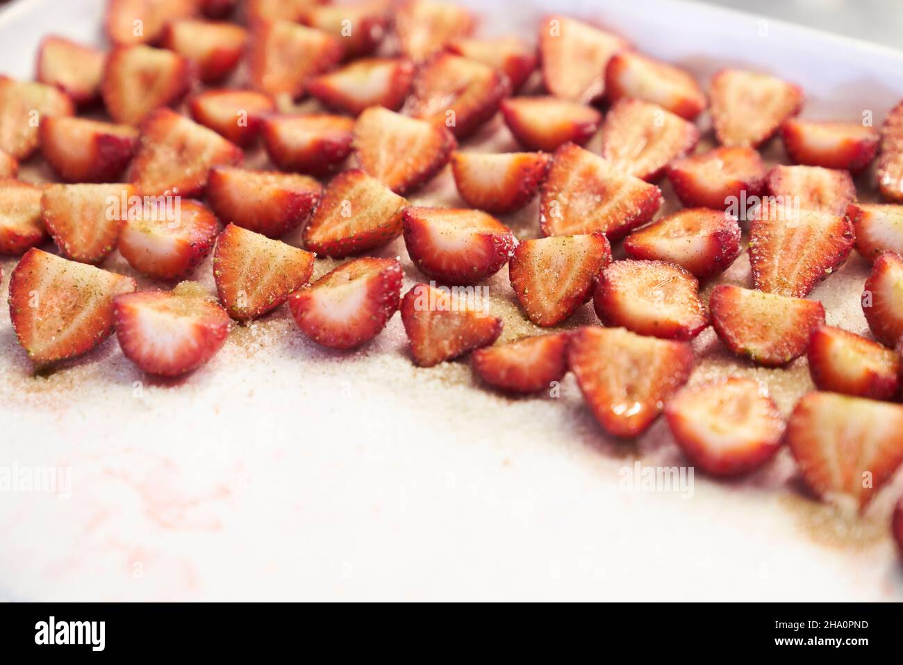 Des tranches de fraises enrorées sont préparées dans une cuisine pour le dessert Banque D'Images