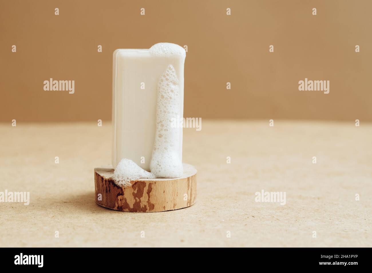 Un morceau de savon naturel bio fait main avec de grandes bulles de mousse sur un podium moderne abstrait. Banque D'Images