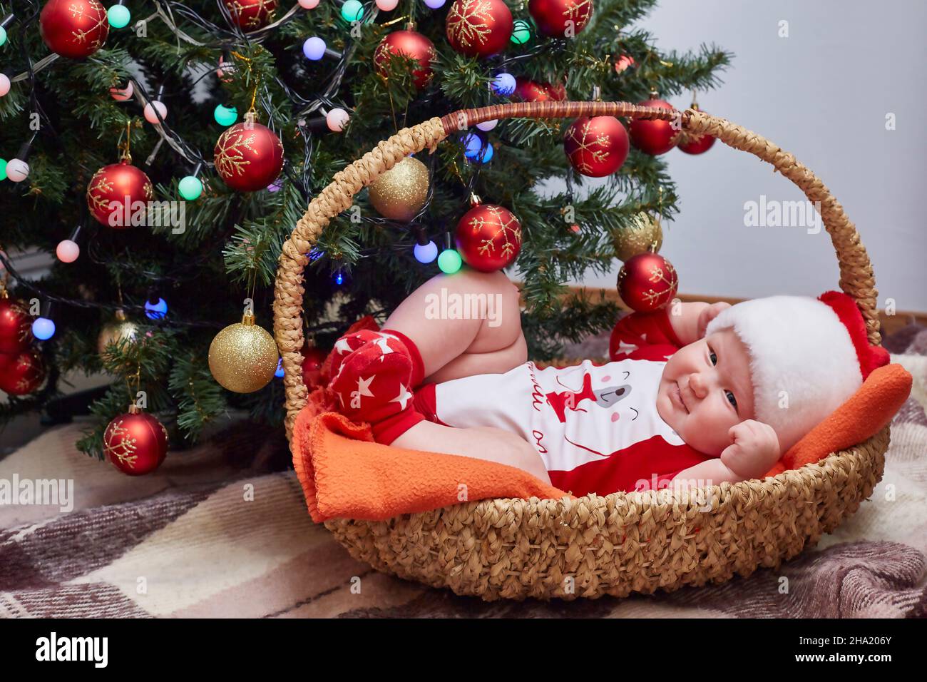 Bebe Souriant Vetu De Vetements Du Pere Noel Est Allonge Dans Un Panier Sous L Arbre De Noel A La Maison Style De Vie Espace Copie Photo Stock Alamy