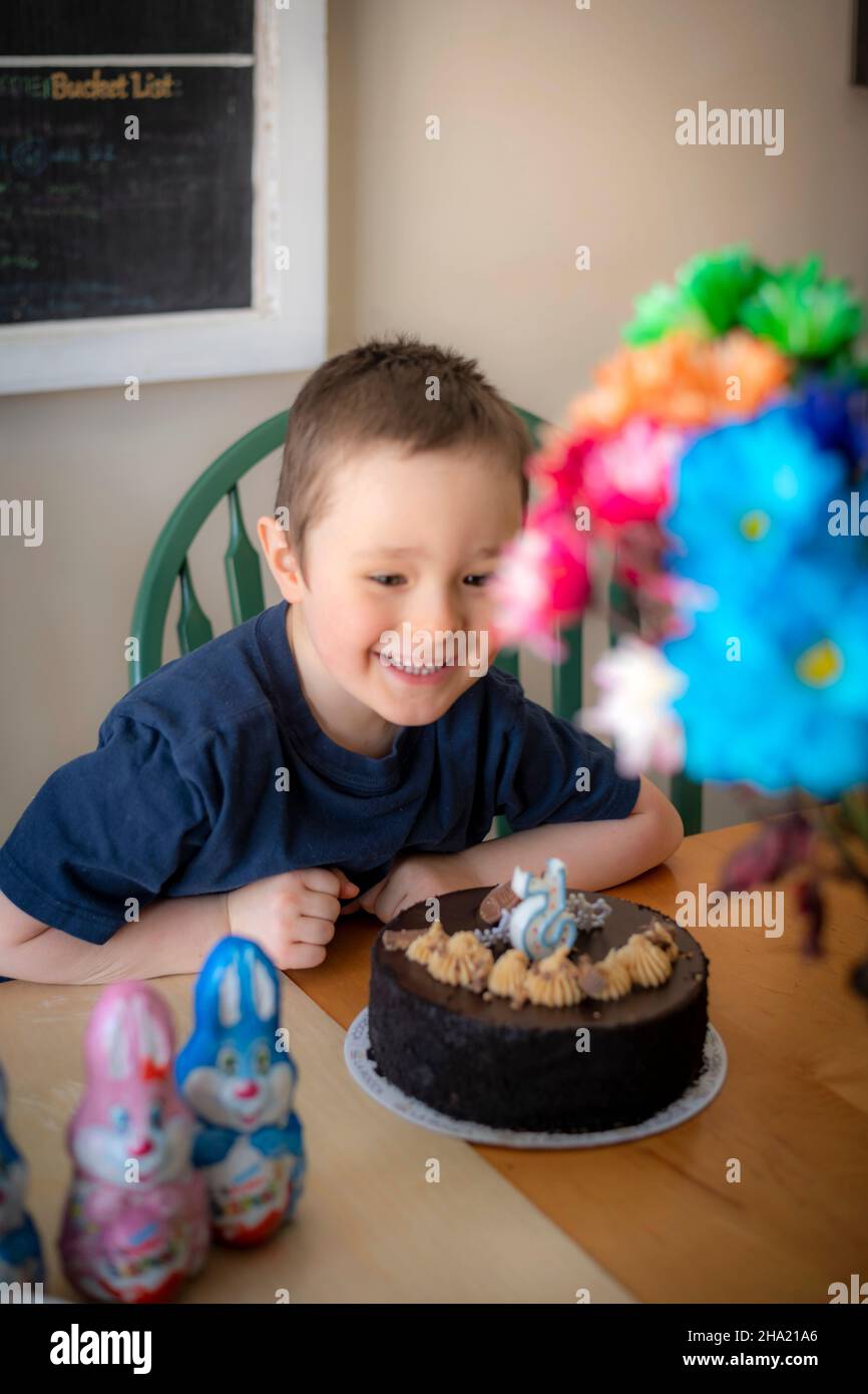 Garçon célébrant son anniversaire de 5 ans à une table avec un gâteau et une bougie sous la forme de la figure 5 Banque D'Images