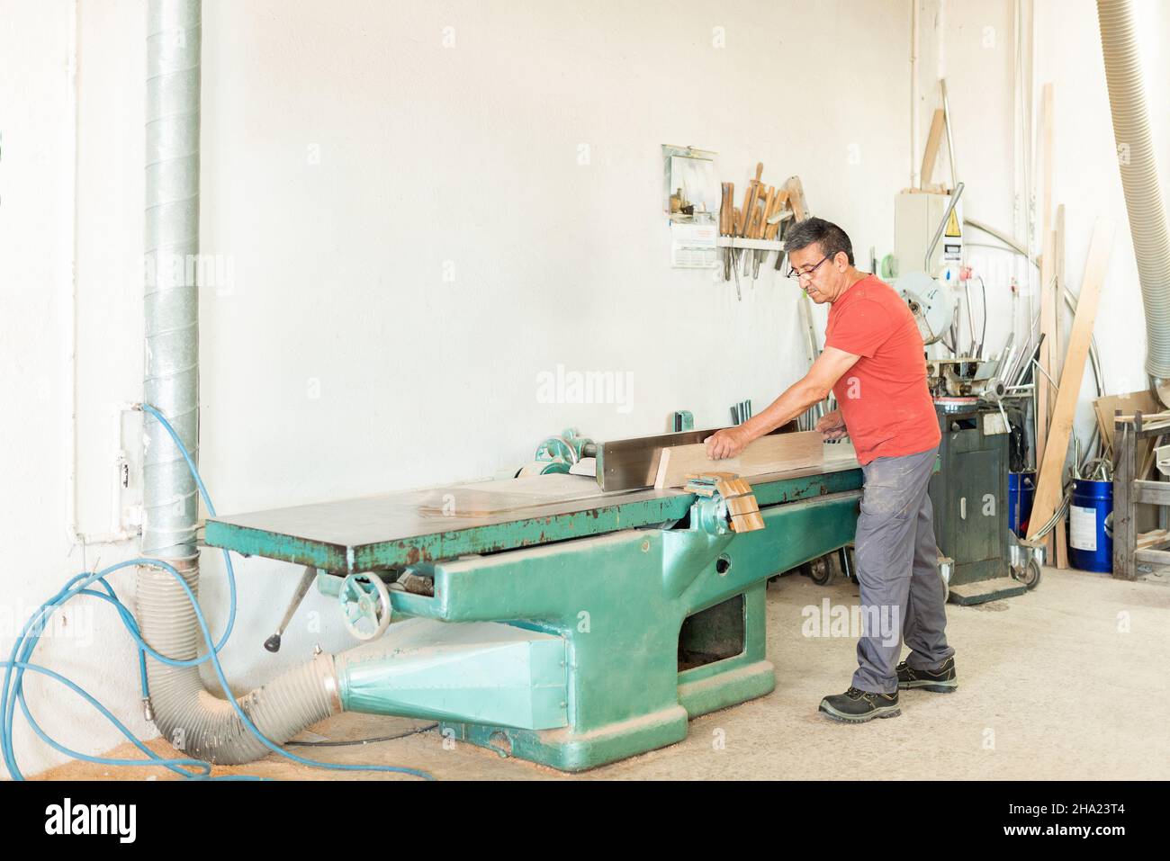 Homme adulte travaillant manuellement avec une machine de rabotage du bois Banque D'Images