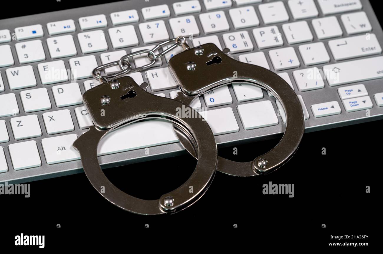 Clavier et menottes avec voyants DEL allumés.Concept de cybercriminalité Banque D'Images