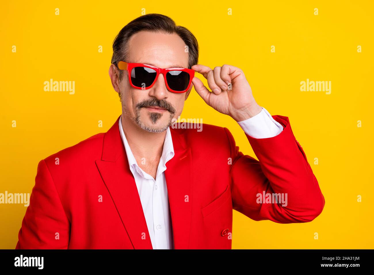 Portrait de l'âge moyen bien habillé homme porter des lunettes de soleil appréciant partie temps libre isolé sur fond jaune de couleur Banque D'Images