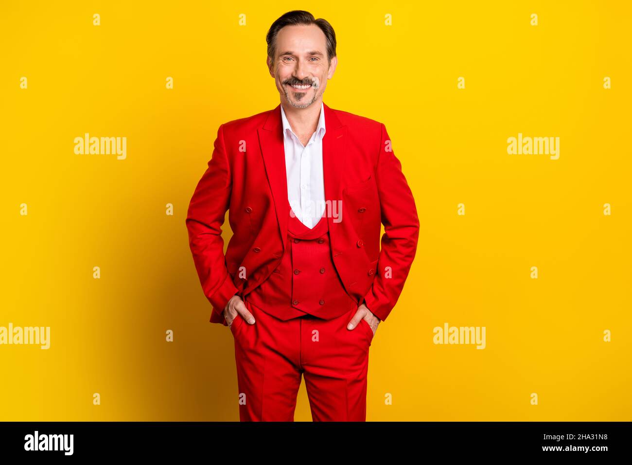 Photo d'un jeune homme d'affaires dans un costume rouge trois pièces luxueux millionnaire isolé sur fond jaune Banque D'Images