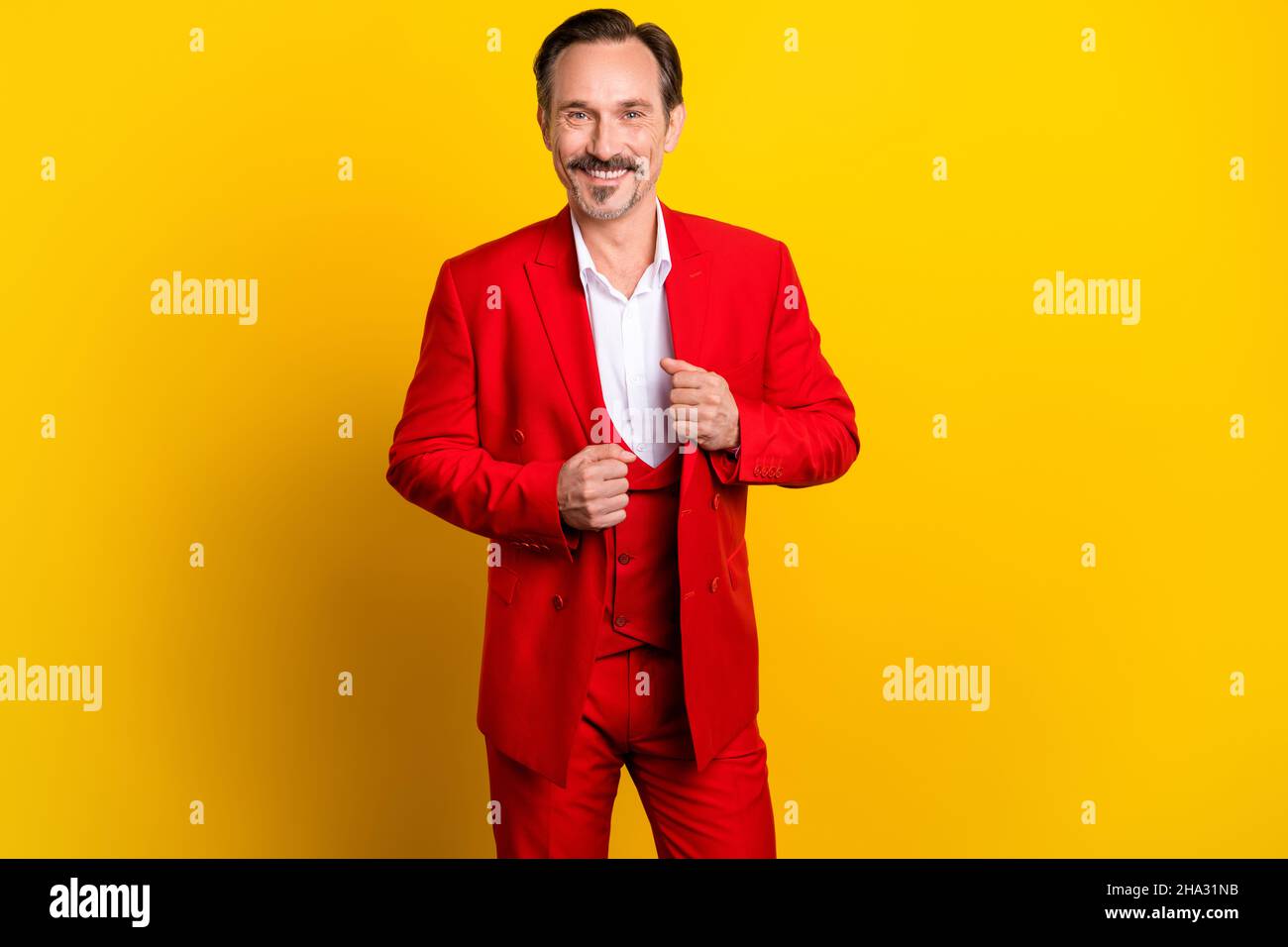 Photo d'un homme d'affaires bien habillé en costume rouge vif se préparer à la fête isolée sur fond jaune Banque D'Images