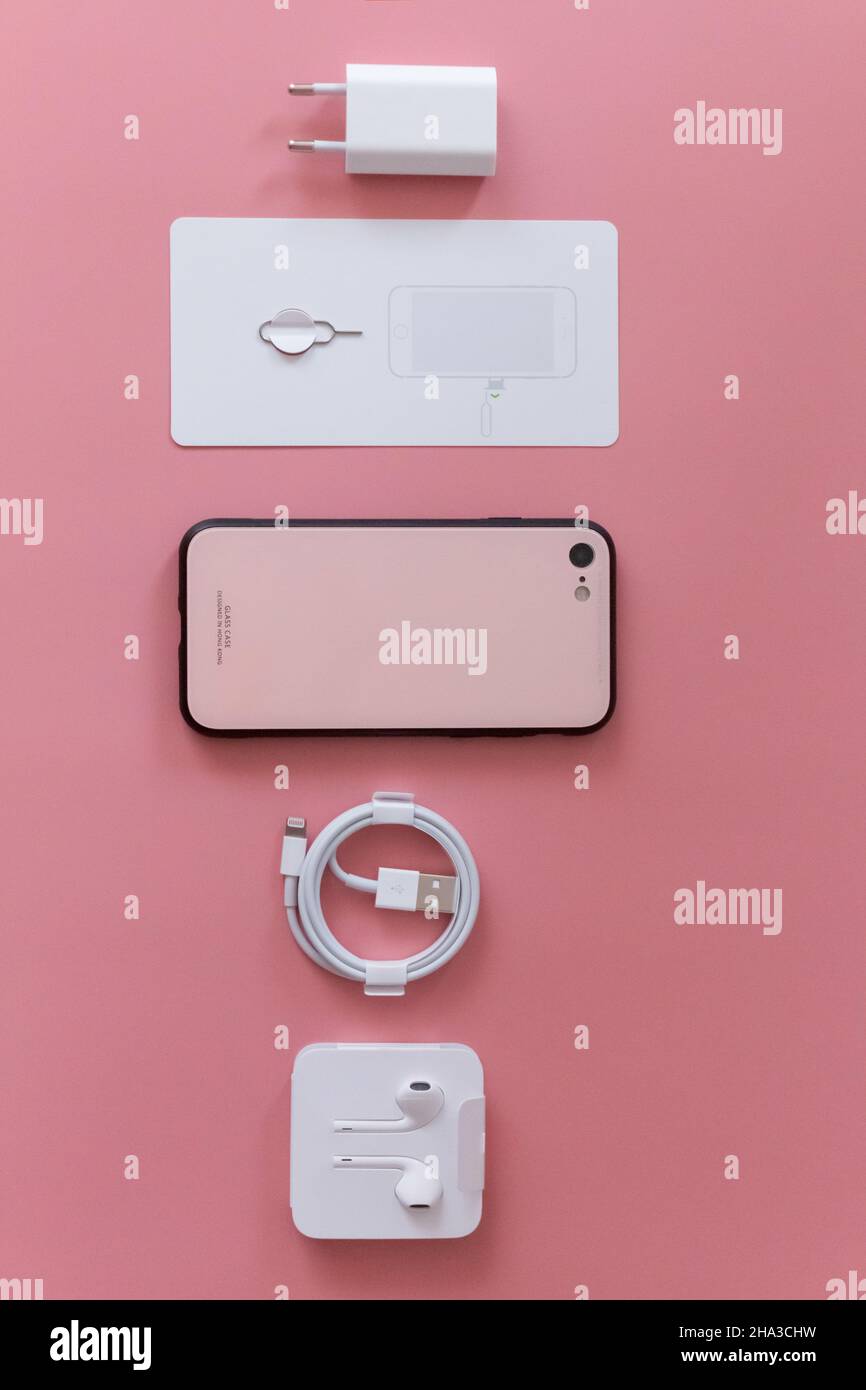 3 avril 2021, Kiev, Ukraine, iPhone se.Pose plate d'accessoires pour smartphone modernes, chargeur et écouteurs sur fond rose Banque D'Images