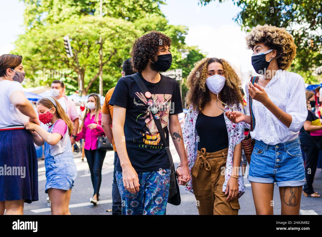 Les jeunes brésiliens portant des masques faciaux parlent et marchent à la foire hippie de Belo Horizonte à Belo Horizonte, Minas Gerais, Brésil. Banque D'Images