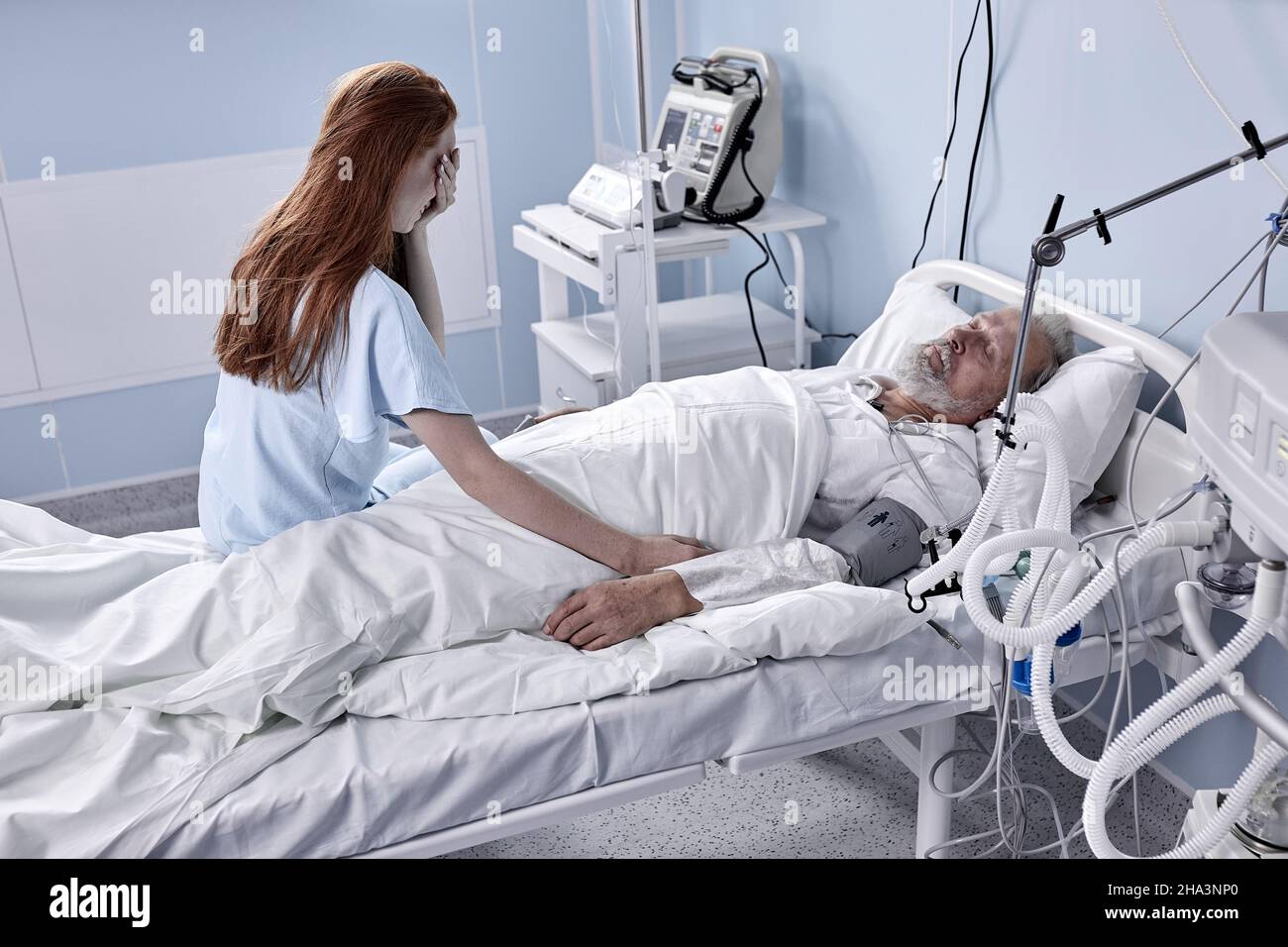 À l'hôpital, un homme malade allongé sur le lit, la femme en visite s'assoit avec tristesse à côté de lui et prie pour sa récupération rapide.Bleu et couleur mélancolique de la scène.Vous Banque D'Images