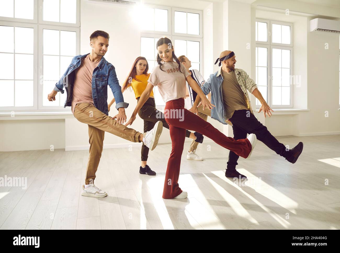 Groupe de jeunes danseurs professionnels souriants et heureux qui s'amusent dans une salle de danse moderne Banque D'Images