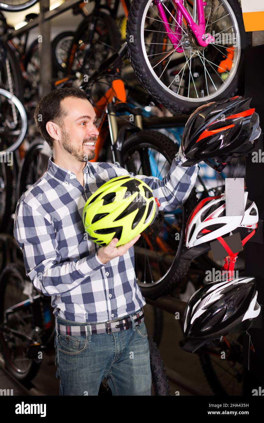 Biker 27-36 ans choisit pour lui-même un casque confortable pour la conduite à vélo. Banque D'Images