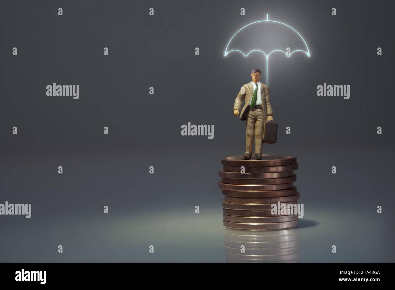 Homme miniature debout sous un parapluie éclairé sur un tas de pièces de monnaie Banque D'Images