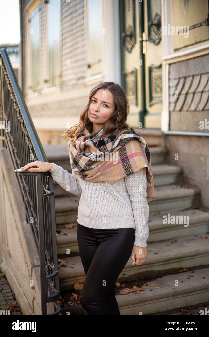 Jeune femme blanche européenne avec cheveux bruns dans un pull gris dans  une écharpe avec des escaliers derrière Photo Stock - Alamy