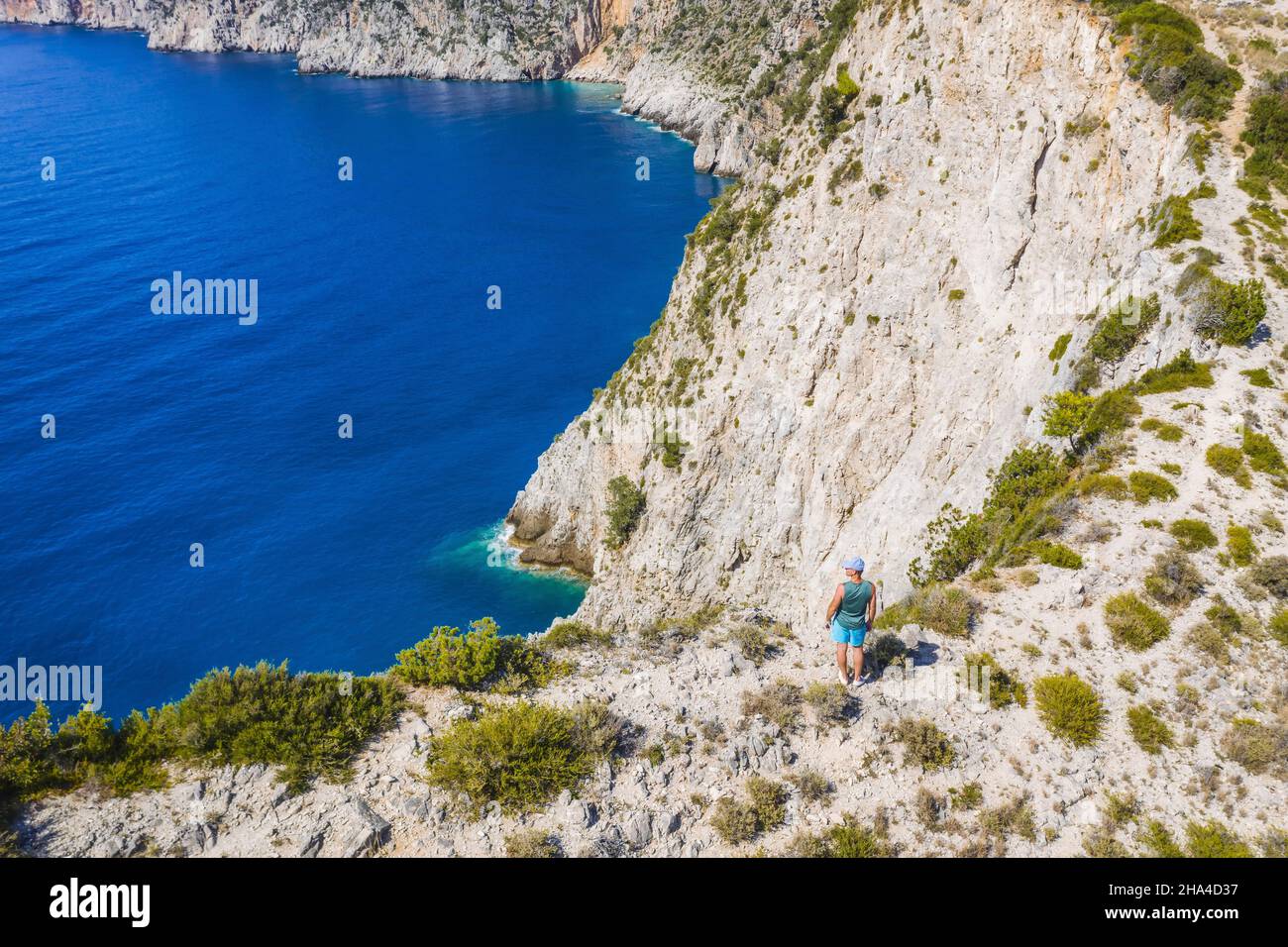 photo aérienne de l'homme voyageur sur le bord de la falaise de la belle et pittoresque côte rocheuse près du village d'assos sur l'île ionienne cefalonia, grèce. Banque D'Images