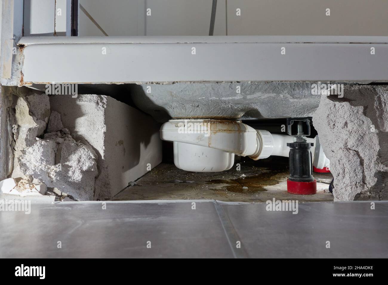 Fuite siphon d'un bac de douche dans la salle de bains, cause des dégâts d'eau.Les carreaux et la maçonnerie ont été retirés pour la réparation et le séchage de la construction.La cause est Banque D'Images