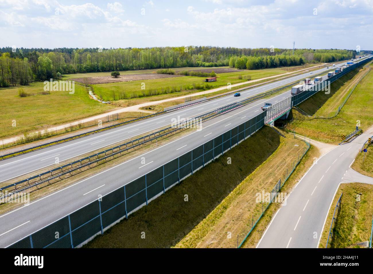 Voitures et semi-camions de fret roulant sur l'autoroute très fréquentée à travers le pays en belle soirée d'été. Les gens qui voyagent sur la route sur l'autoroute à g Banque D'Images