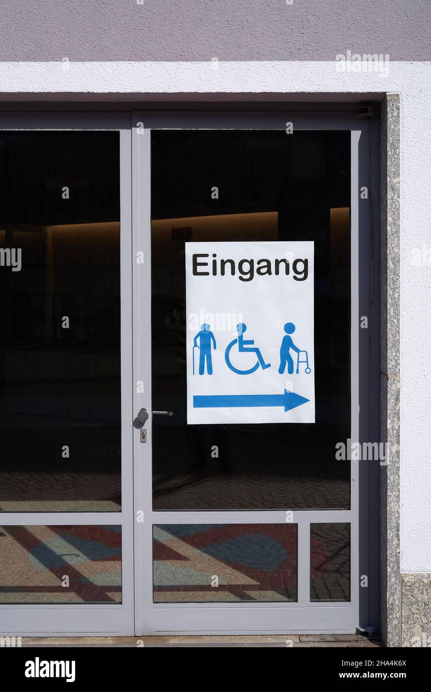 Panneau sur porte vitrée disant: Entrée (allemagne: Eingang ).Livre blanc avec symboles vectoriels des personnes handicapées et handicapées physiques.Vue avant. Banque D'Images