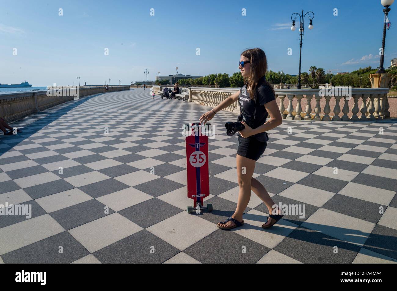 skater fille de patinage et de saut sur terrazza mascagni à livourne, en italie. son grand belvédère sinueux vers la mer avec une surface pavée de 8700 m² comme un damier et 4,100 balusters Banque D'Images