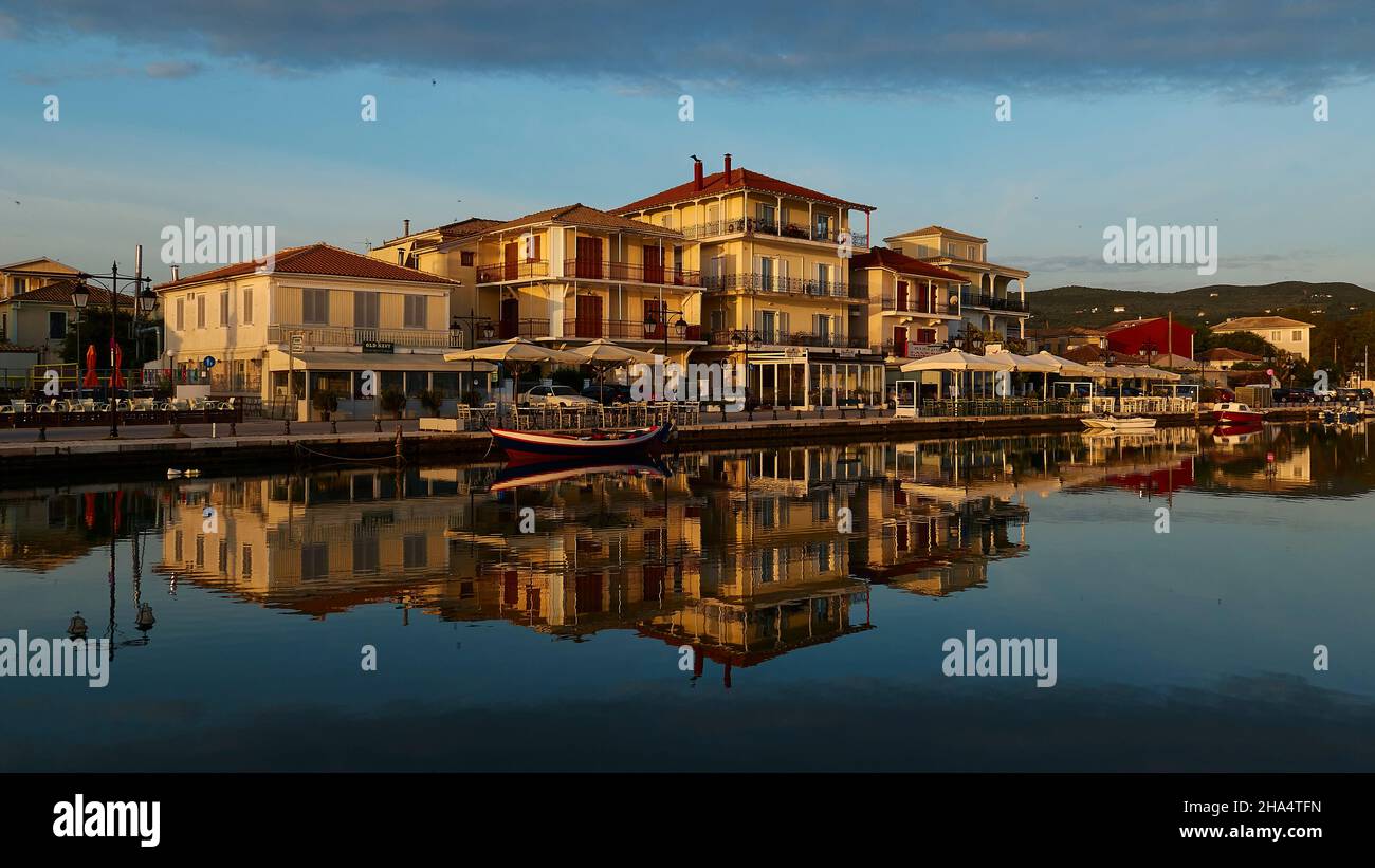 grèce,iles grecques,iles ioniennes,lefkada ou lefkas,ville de lefkada,capitale,lumière du matin,aube,rangée de maisons se reflète dans l'eau calme du canal,bleu ciel,au-dessus de gris nuage Banque D'Images