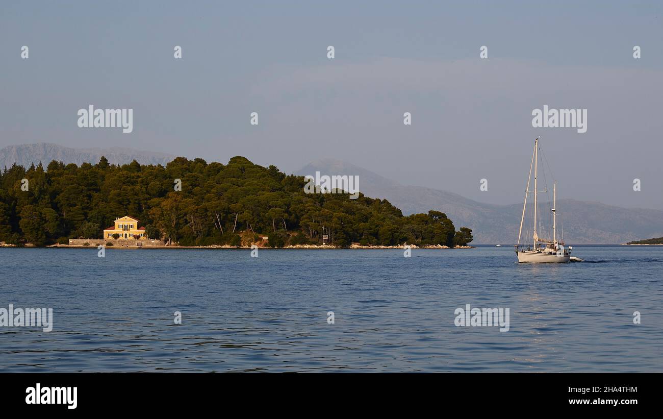 grèce,îles grecques,îles ioniennes,lefkada ou lefkas,baie de nidri,vue de l'île offshore à mi-distance,continent en arrière-plan,bateau à voile va de droite à gauche,villa sur l'îlot Banque D'Images