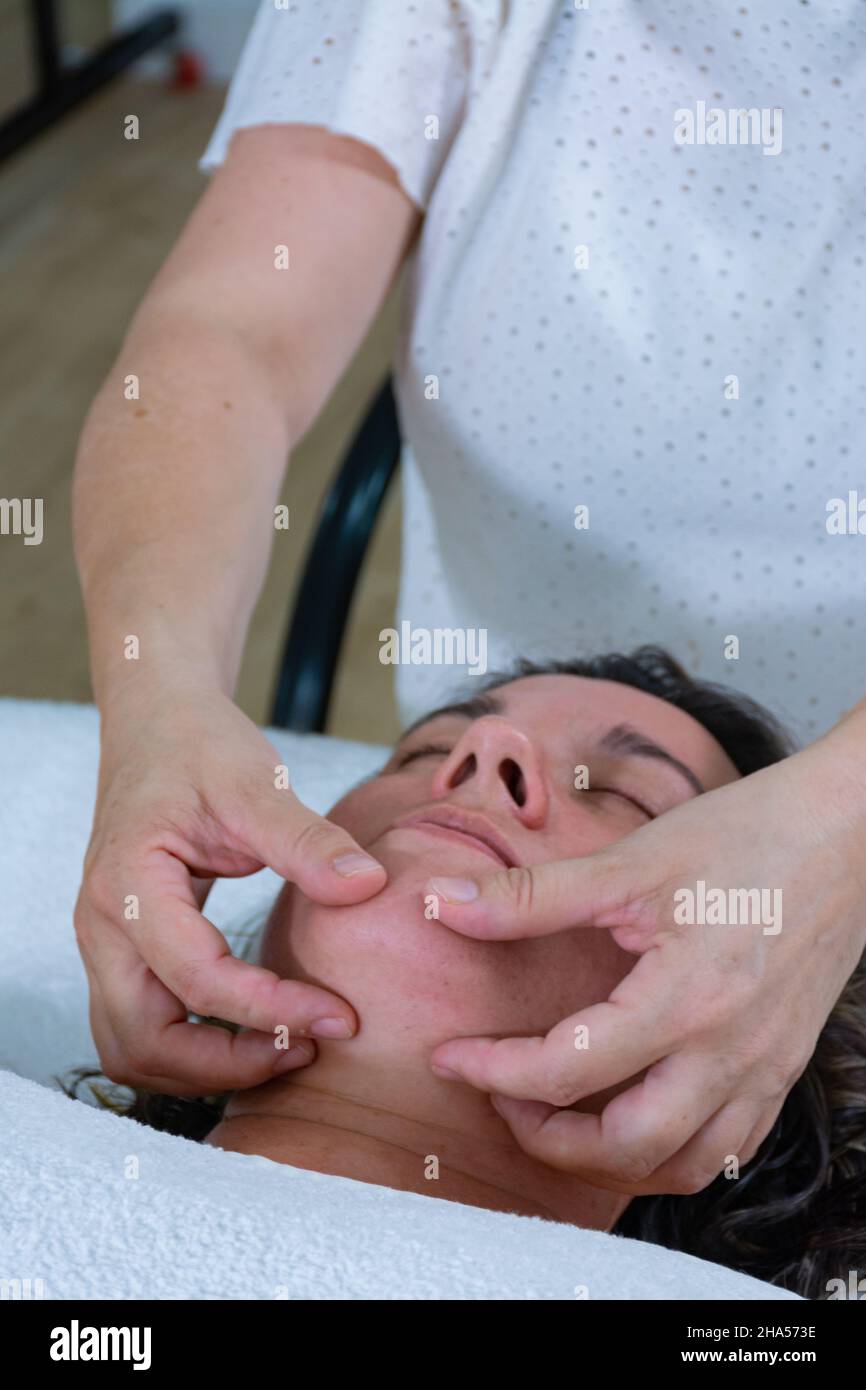 Femme masseuse donnant un massage des mains à la mâchoire d'une autre femme.Massage énergétique ou reiki Banque D'Images