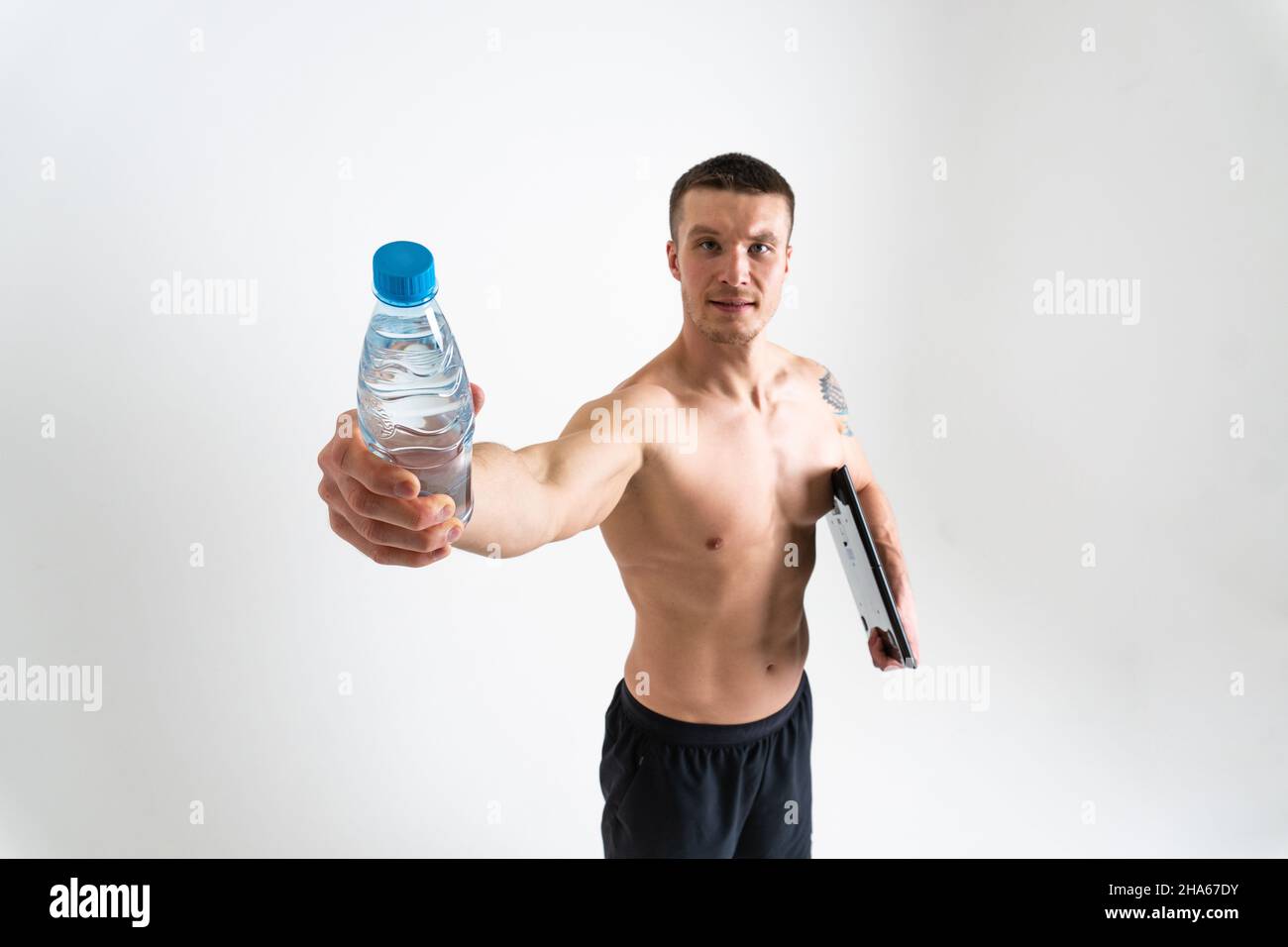 La forme physique à l'eau potable est pompée avec une serviette sur un fond blanc, le corps d'athlète de forme physique isolé, sportswear homme sportif, sportivité de force parfaite, Banque D'Images