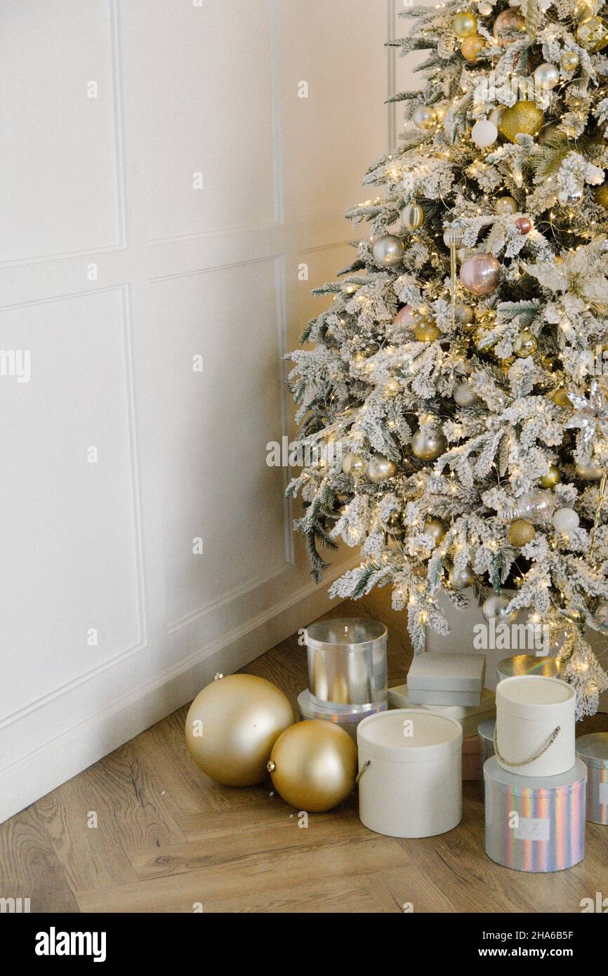 Sapin de noël blanc avec des jouets et des boîtes-cadeaux dorés et roses Banque D'Images