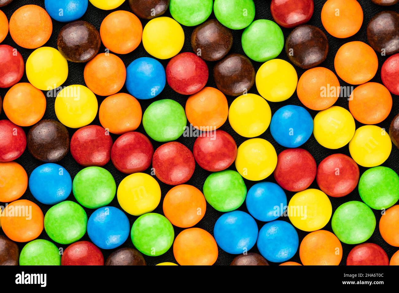 Vue de dessus de grains de chocolat multicolores sur fond noir.Pilules sucrées au chocolat. Banque D'Images