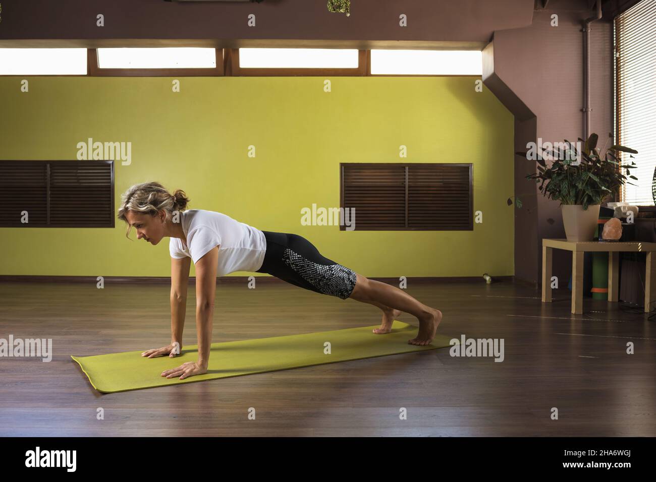 Une femme exécute l'exercice kumbhakasana, pose de planche, s'entraîne dans le studio sur un tapis Banque D'Images