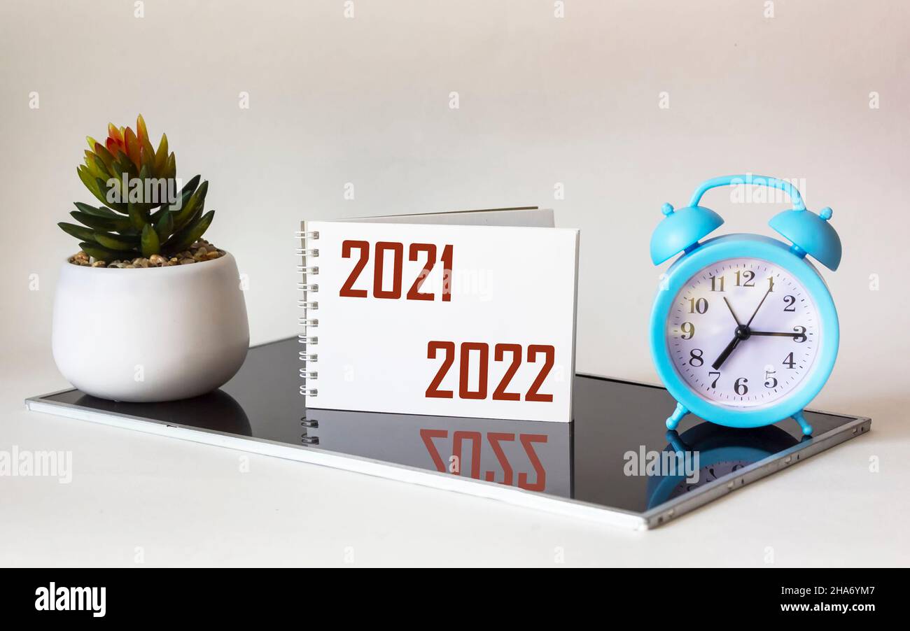 2021-2022.Écriture de l'inscription dans un bloc-notes blanc, sur fond noir et blanc, décision de conception.À proximité d'une horloge et d'un cactus Banque D'Images