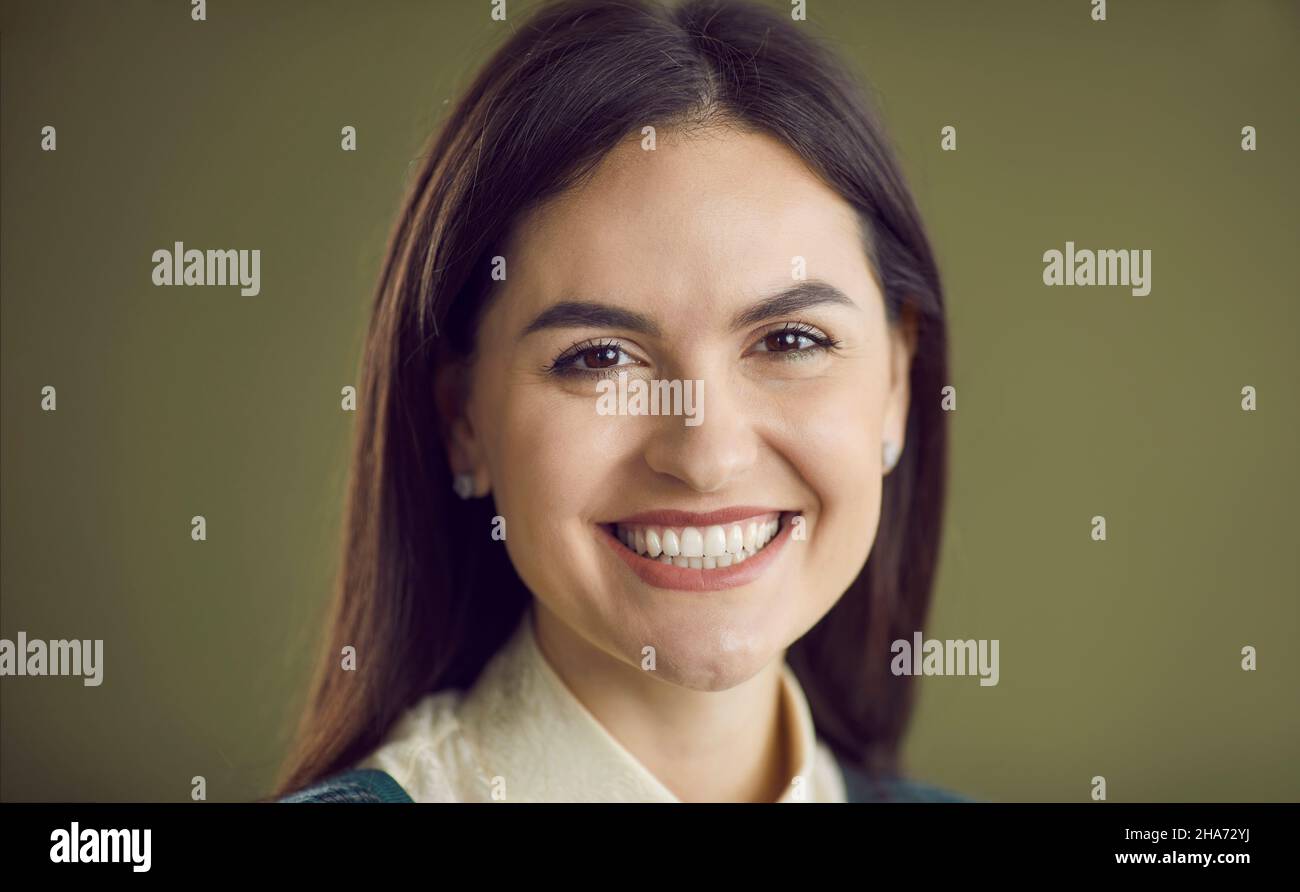 Portrait d'une jeune femme heureuse avec un beau sourire sur un fond de studio vert Banque D'Images