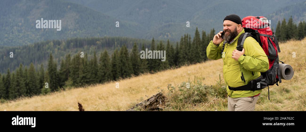 voyageur parlant au téléphone en haut de la chaîne de montagnes.Un jeune touriste avec un sac à dos et une veste a peur pendant ses vacances et sa randonnée Banque D'Images