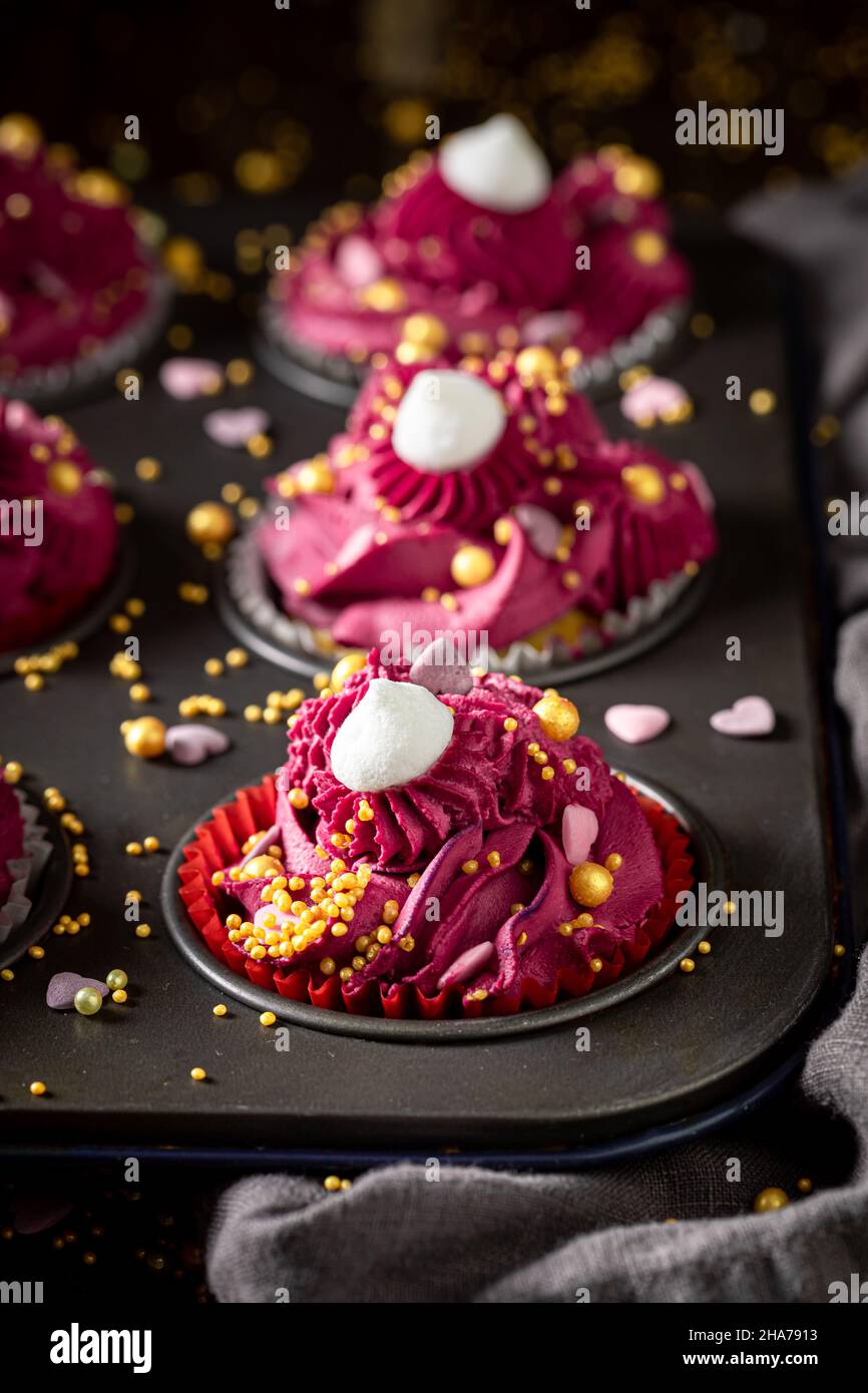 Délicieux petits gâteaux rouges faits de crème fouettée pour la graisse jeudi.Dessert rouge époustouflant avec des saupoudrés dorés. Banque D'Images