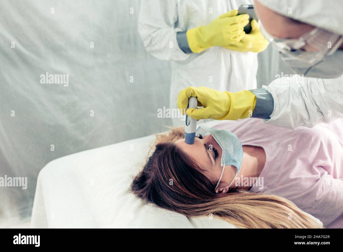 Médecins méconnaissables dans un hôpital de campagne prenant la fièvre un patient Banque D'Images