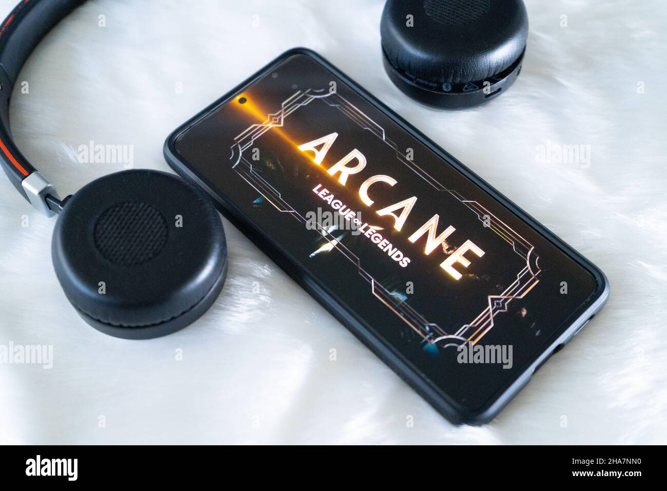 Smartphone mobile sur un support avec un casque près de lui placé sur une surface de neige en fourrure fouleuse en regardant le populaire spectacle netflix d'Arcane Banque D'Images
