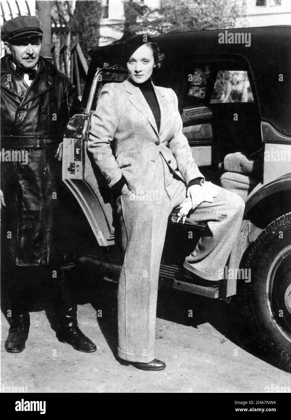 MARLENE DIETRICH au début de 1933 portant Beret avec veste et pantalon avec  son chauffeur HARRY WRIGHT à côté de sa voiture Rolls Royce quittant  Paramount Studios à Hollywood après une journée