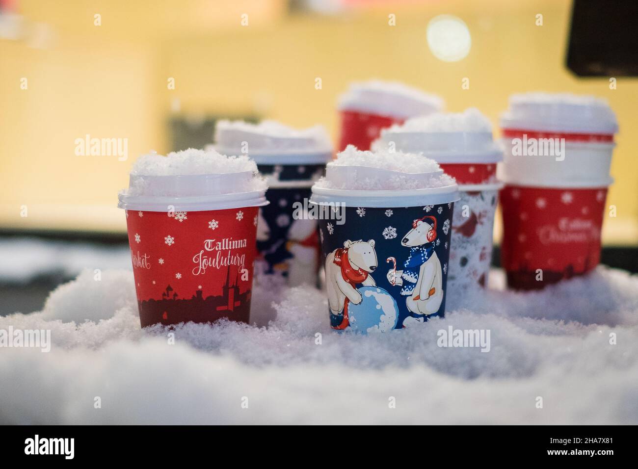 Tasses à café en papier utilisées avec motif de vacances laissées sur un banc enneigé en soirée d'hiver.Boisson chaude de Noël. Banque D'Images