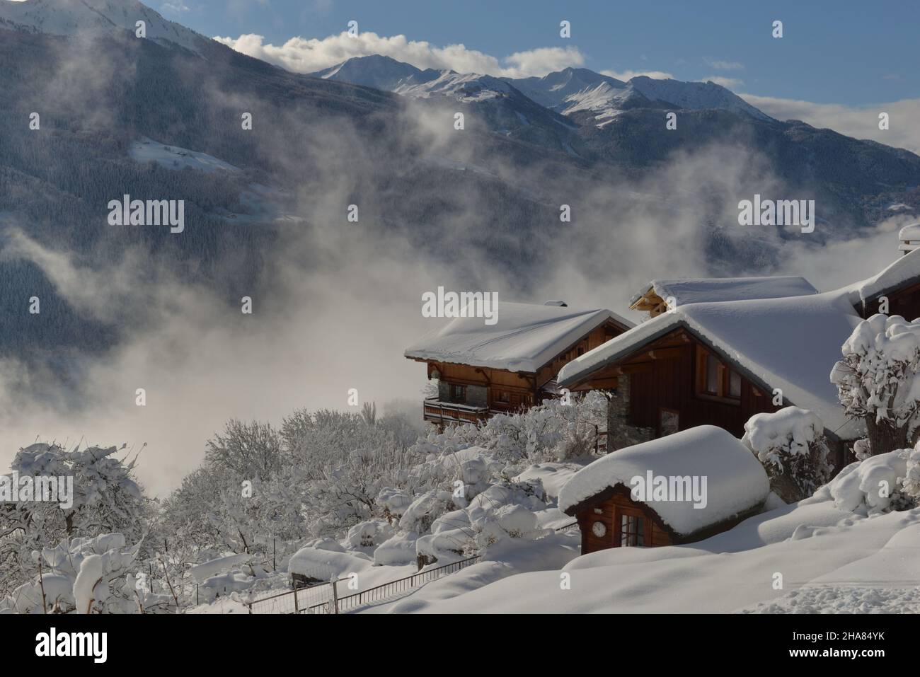 chalets en bois dans un village alpin recouvert de neige dans un paysage de montagne Banque D'Images