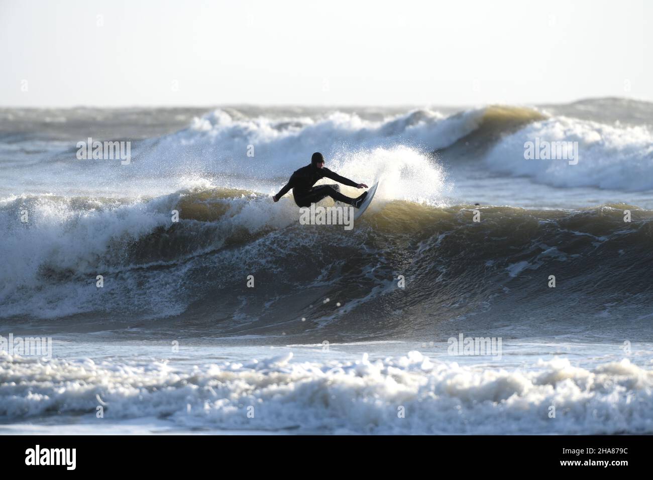 Tirer le meilleur parti des vagues de Storm Barra un surfeur en combinaison d'hiver complète atteint le sommet de la vague. Banque D'Images