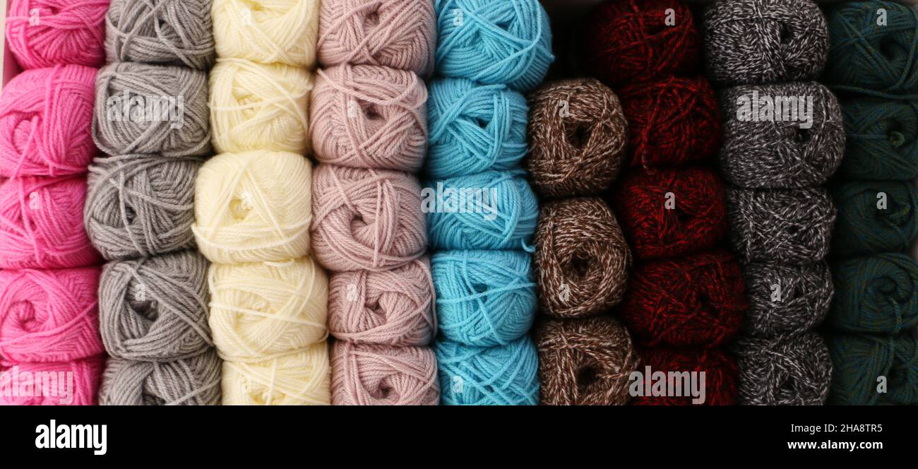 Fils à tricoter colorés alignés sur la tablette. Ils sont généralement utilisés pour tricoter les cardigans et les gilets. Banque D'Images