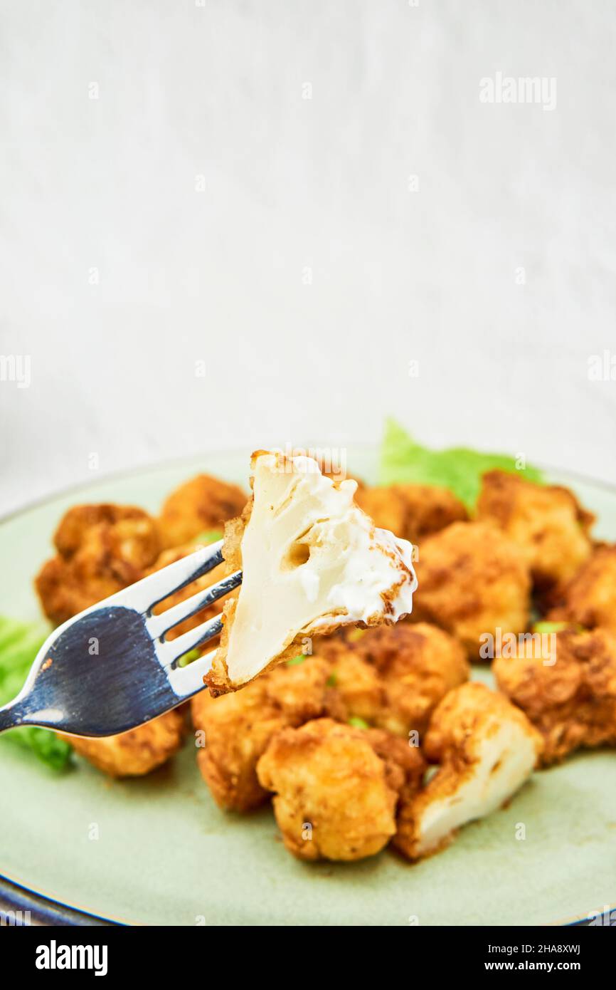 Ailes de buffle de chou-fleur vegan sur une fourchette.Plats végétariens savoureux en gros plan. En-cas croustillants de chou-fleur frit Banque D'Images