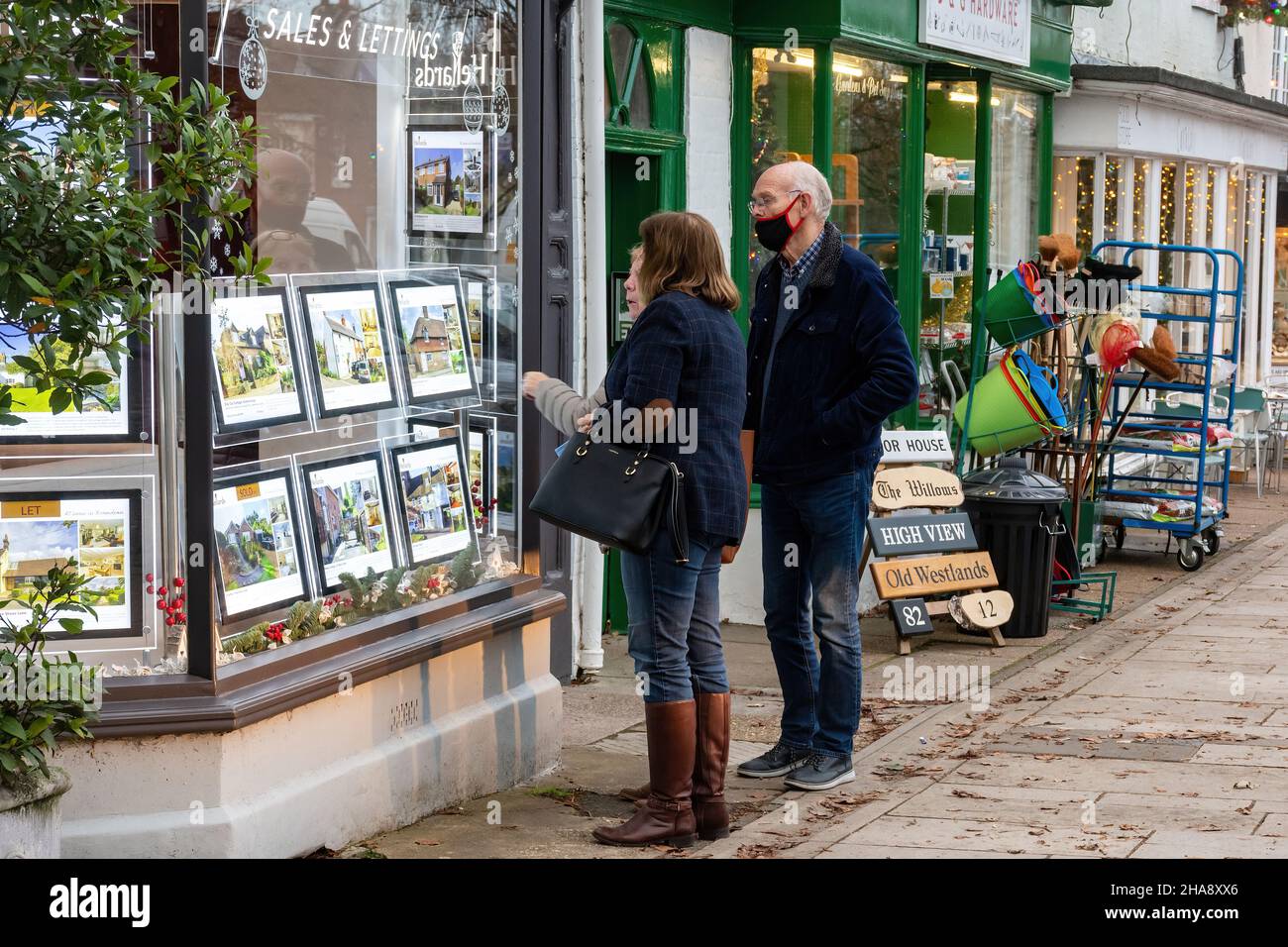 Personnes regardant les détails de la propriété dans une fenêtre de magasin d'agents immobiliers, Hampshire, Angleterre, Royaume-Uni Banque D'Images