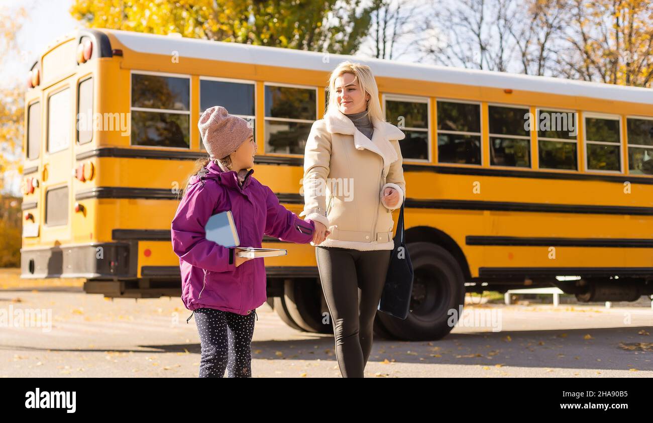 Bonne fille regardant la mère par autobus scolaire Banque D'Images