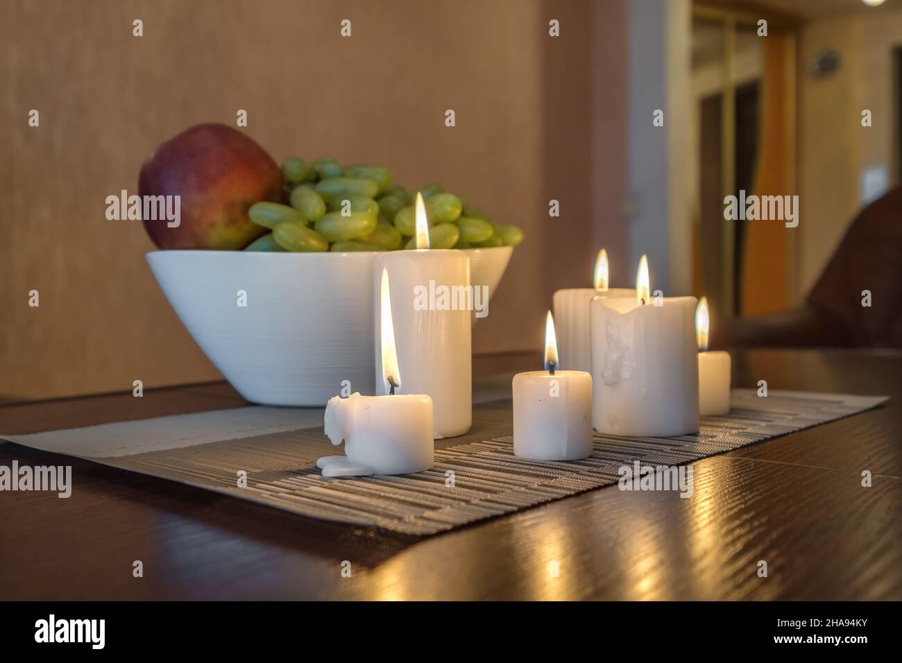 bougies allumées et vase avec pommes de fruits et raisins sur la table près de la lampe Banque D'Images