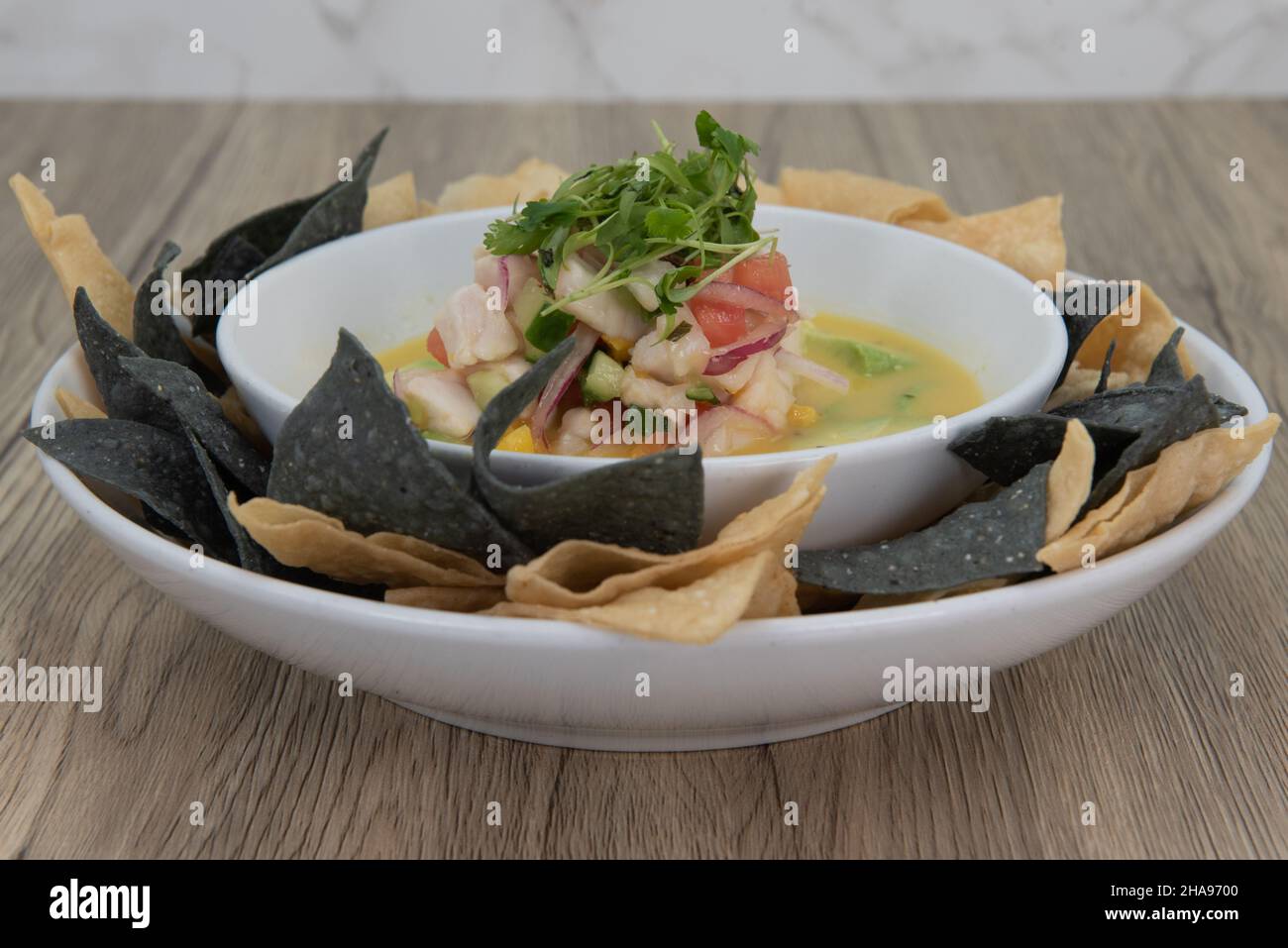 Présentation artistique d'un bol de céviche trempée entouré de morceaux de nachos de couleur alternée. Banque D'Images